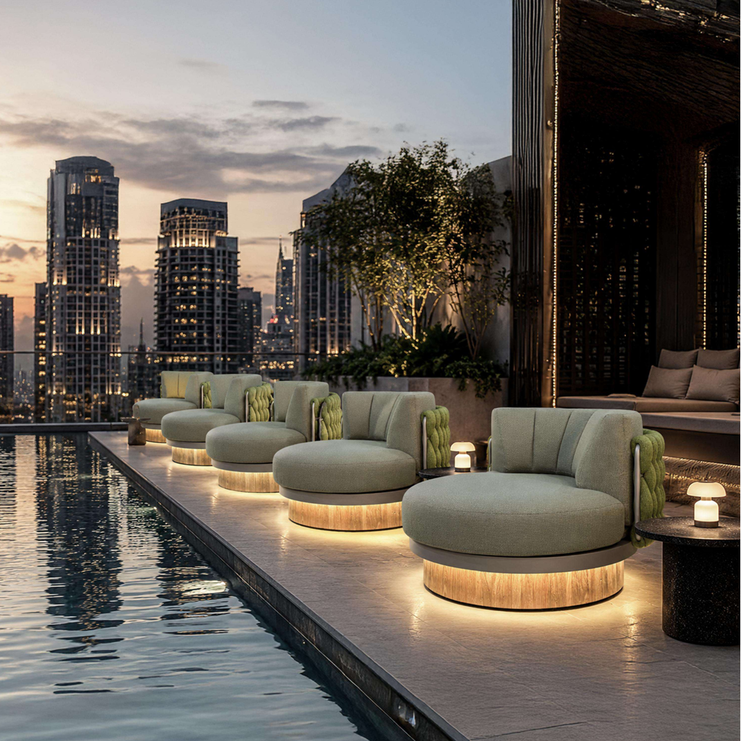 Modern outdoor lounge furniture by a rooftop pool at dusk, featuring round upholstered seating with warm under-seat lighting and a city skyline in the background.